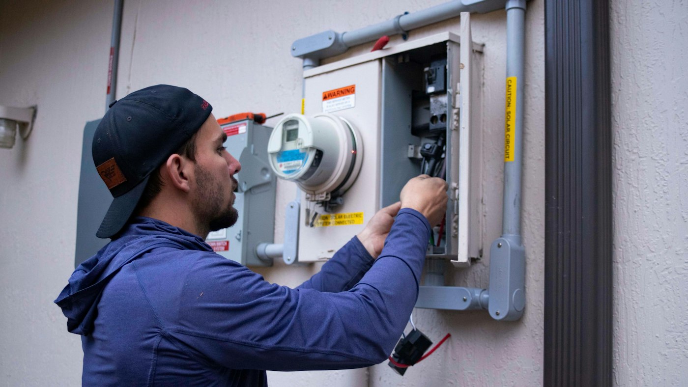 A technician in a cap working on an electrical panel