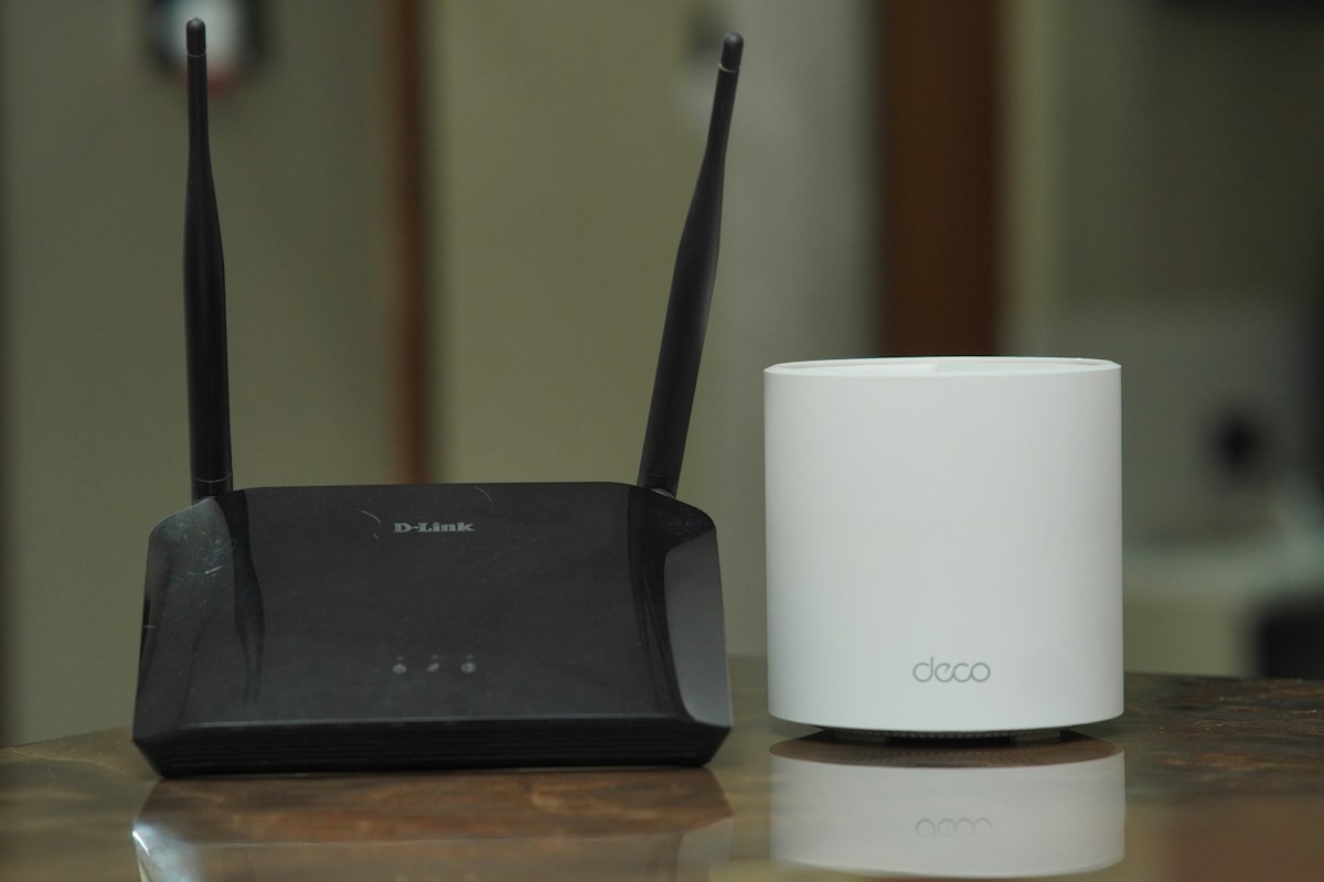 A black router and a white mesh Wi-Fi point on a table